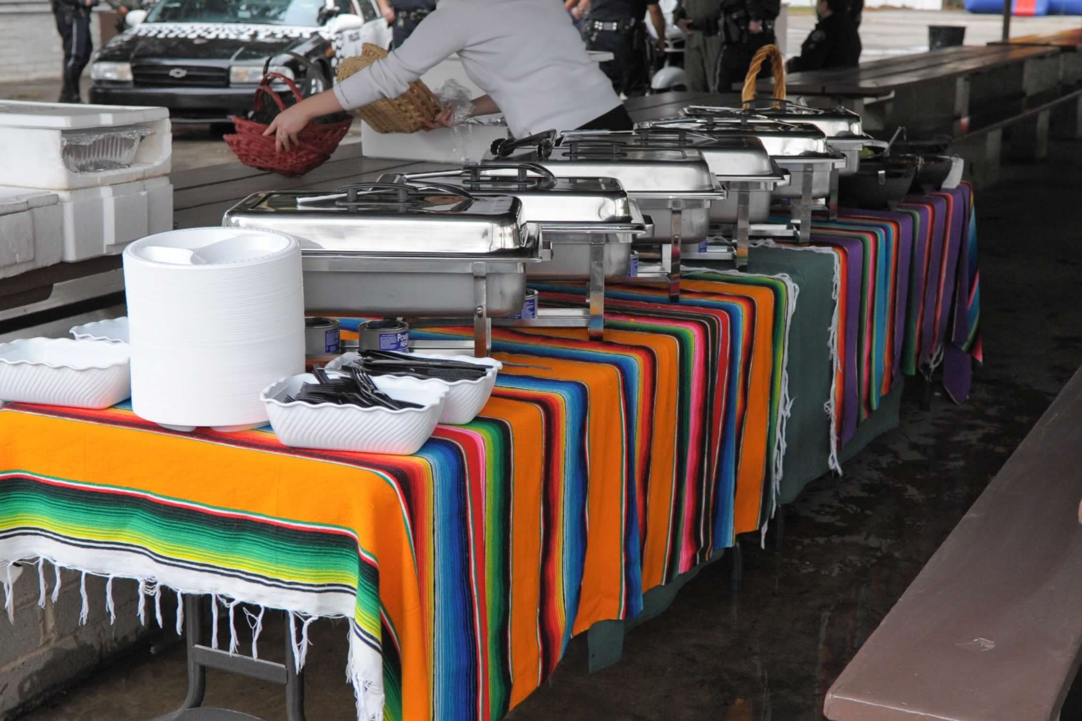 A long catering buffet dressed in striped serape runners, chafing dishes and serving bowls set out down the table.