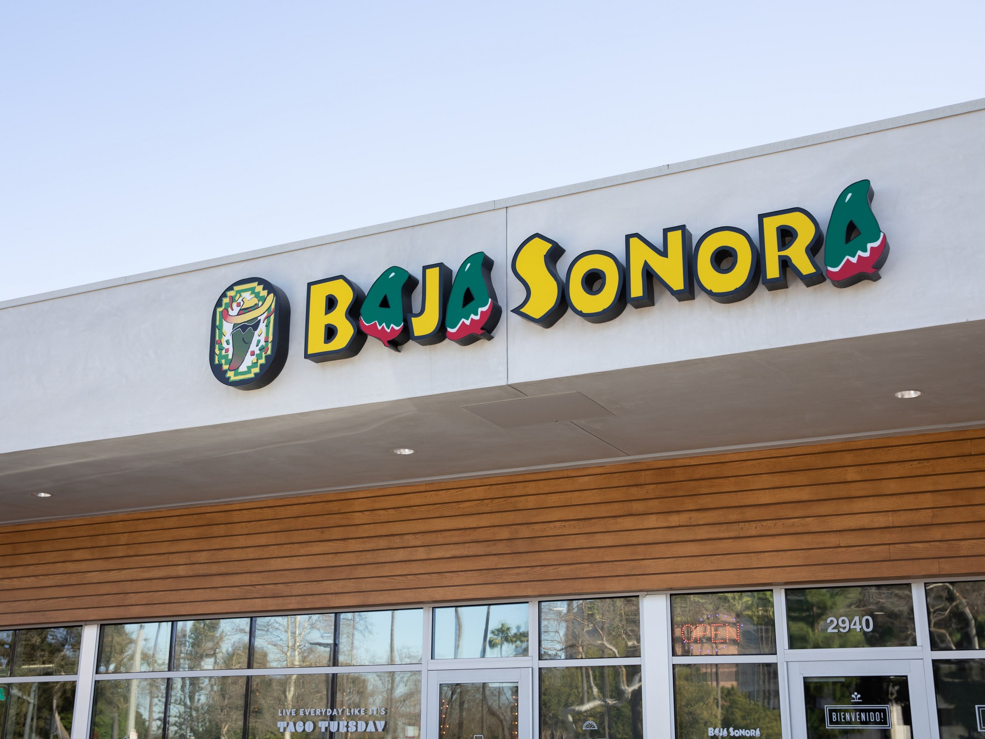 The Baja Sonora storefront: tall yellow and green letters spelling the restaurant's name above a cedar-clad front and glass doors.